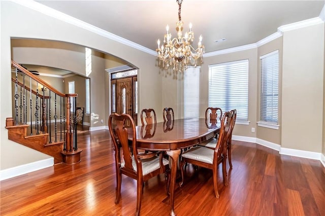 dining space with arched walkways, ornamental molding, stairs, and wood finished floors