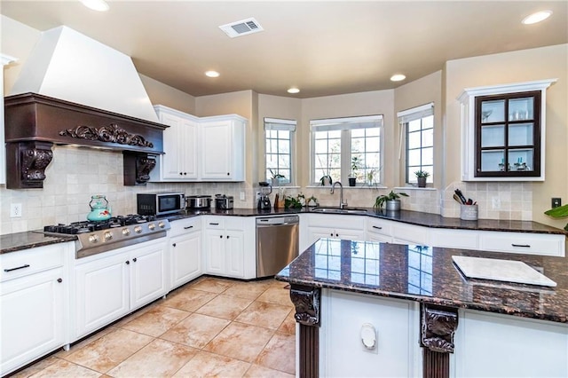 kitchen featuring visible vents, custom range hood, a sink, stainless steel appliances, and white cabinets