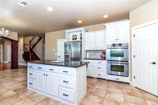 kitchen featuring visible vents, backsplash, a center island, appliances with stainless steel finishes, and white cabinetry