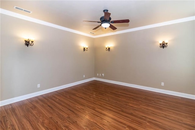 unfurnished room featuring dark wood-style floors, visible vents, crown molding, and baseboards