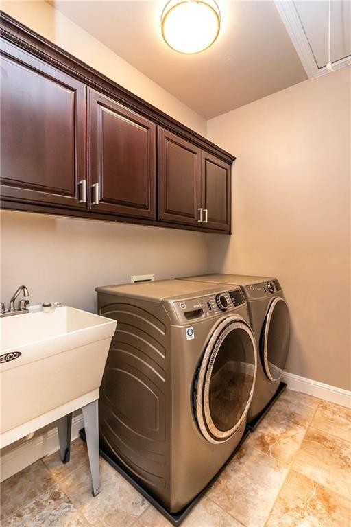 clothes washing area with separate washer and dryer, attic access, cabinet space, and baseboards