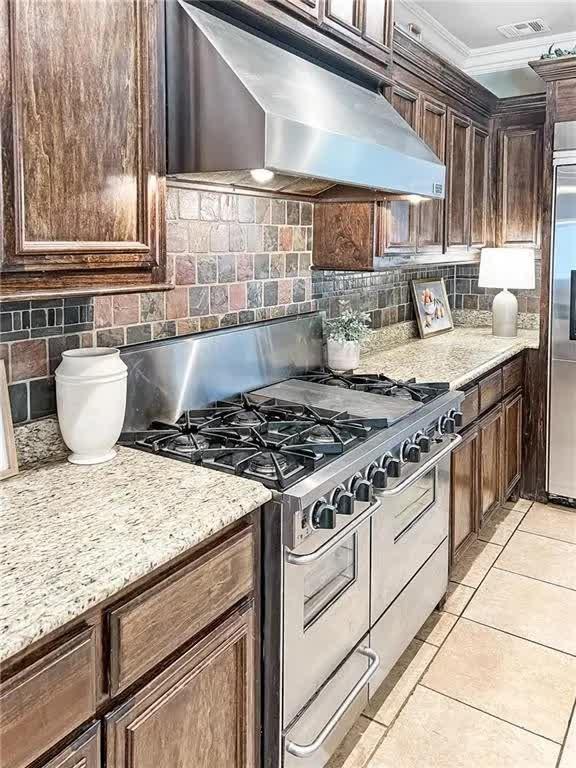 kitchen featuring visible vents, backsplash, stainless steel appliances, and wall chimney exhaust hood