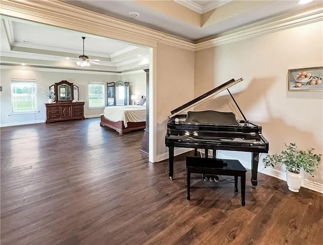 sitting room with a raised ceiling, dark wood-style floors, and ornamental molding