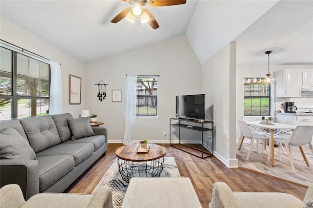 living room featuring vaulted ceiling, baseboards, light wood-type flooring, and ceiling fan