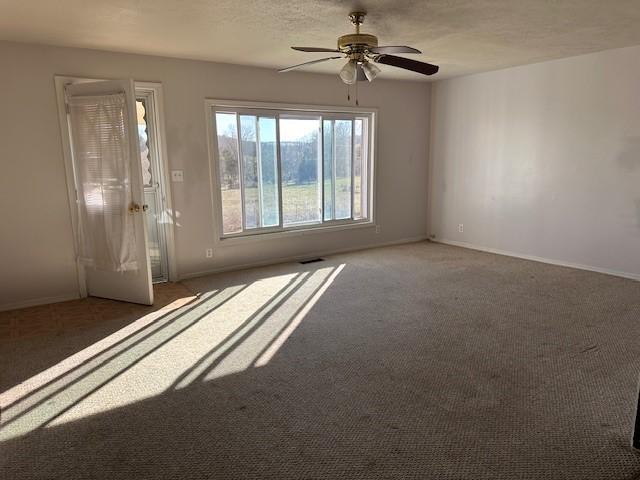 interior space featuring visible vents, baseboards, a textured ceiling, and ceiling fan