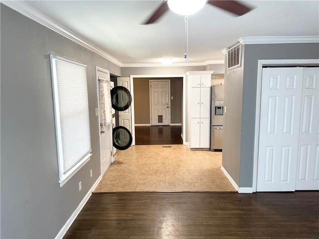 interior space with baseboards, wood finished floors, visible vents, and ornamental molding