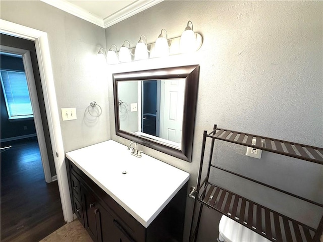 bathroom with ornamental molding, vanity, and a textured wall