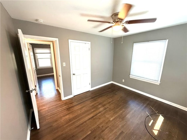 unfurnished bedroom featuring baseboards, ceiling fan, and dark wood-style flooring