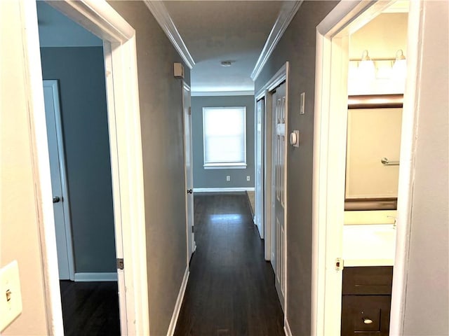 hallway featuring dark wood finished floors, baseboards, and ornamental molding