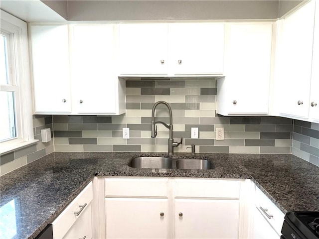 kitchen with dark stone counters, a sink, range with electric stovetop, white cabinetry, and backsplash