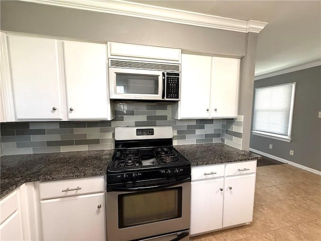 kitchen with dark stone counters, ornamental molding, stainless steel appliances, white cabinets, and backsplash