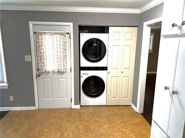 washroom featuring baseboards, stacked washer and clothes dryer, and crown molding