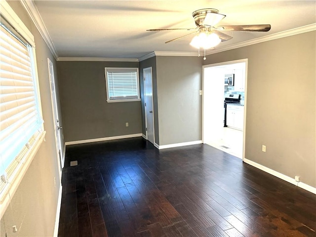 spare room featuring dark wood finished floors, crown molding, and baseboards