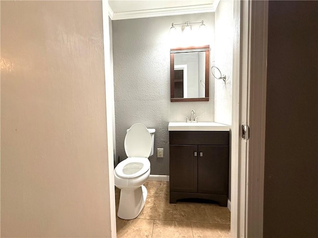 half bath with vanity, baseboards, ornamental molding, toilet, and a textured wall