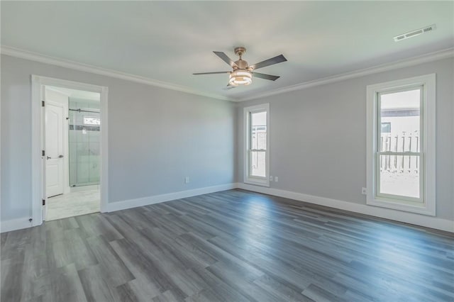 empty room featuring visible vents, wood finished floors, and ornamental molding