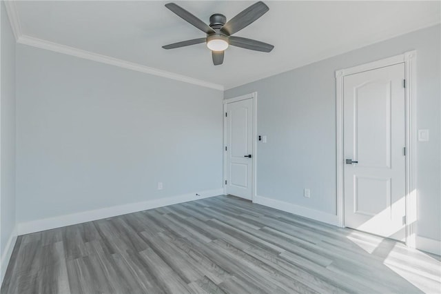 empty room with ceiling fan, baseboards, wood finished floors, and crown molding