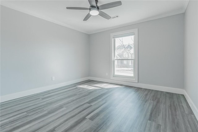 empty room with ceiling fan, crown molding, baseboards, and wood finished floors