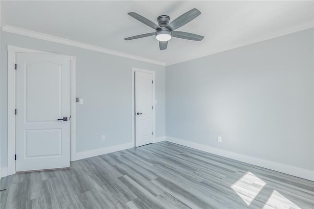 spare room with ceiling fan, wood finished floors, baseboards, and ornamental molding