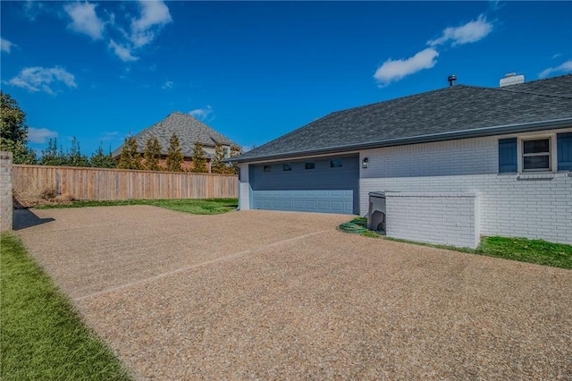 view of home's exterior with brick siding, driveway, and fence