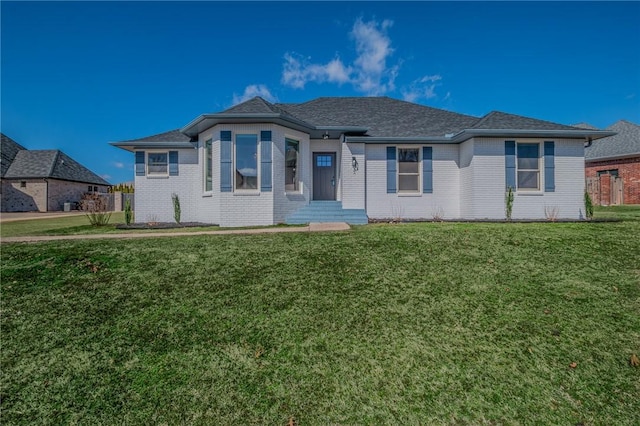 single story home with brick siding, a shingled roof, and a front lawn