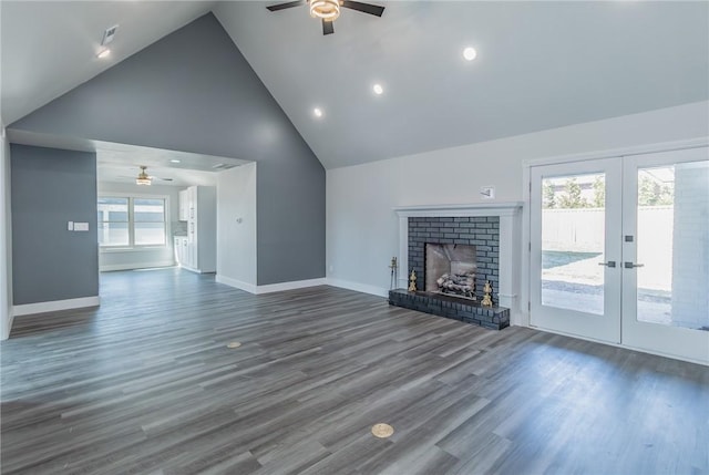 unfurnished living room with a brick fireplace, baseboards, french doors, dark wood-style floors, and high vaulted ceiling