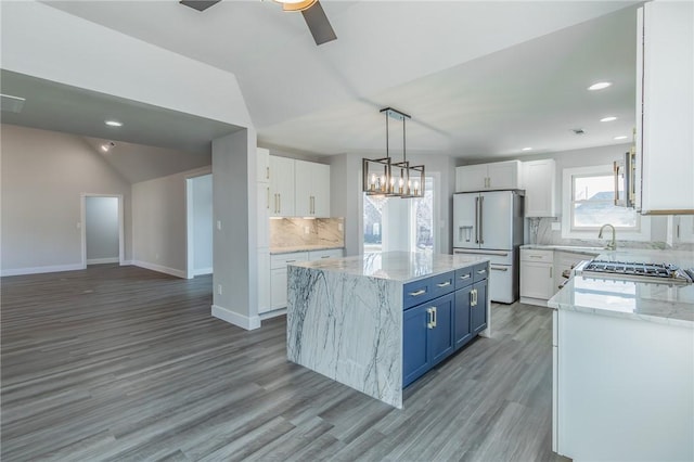 kitchen with blue cabinets, stove, white refrigerator with ice dispenser, and white cabinets