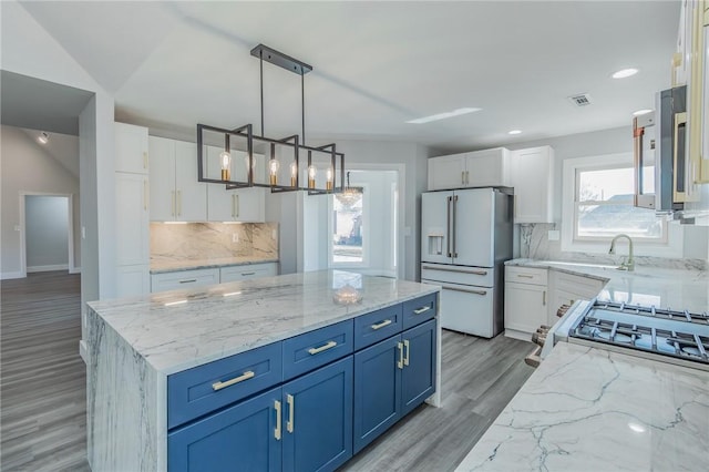 kitchen with a center island, white cabinets, blue cabinetry, and white refrigerator with ice dispenser