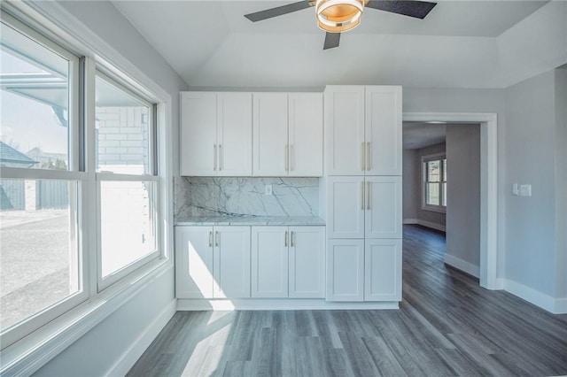 kitchen featuring wood finished floors, baseboards, vaulted ceiling, white cabinetry, and tasteful backsplash