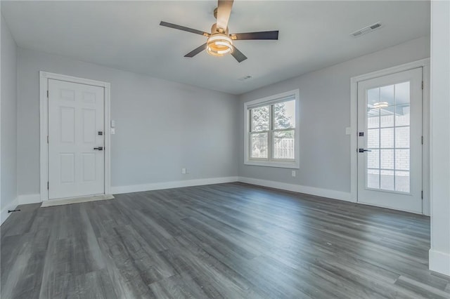 unfurnished living room featuring visible vents, baseboards, and dark wood finished floors