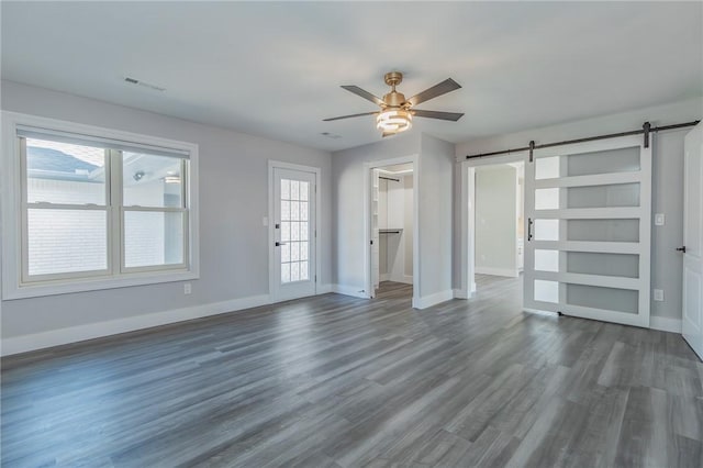 interior space featuring visible vents, dark wood-style floors, a barn door, baseboards, and ceiling fan