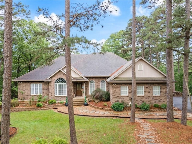 ranch-style house featuring brick siding, roof with shingles, and a front lawn