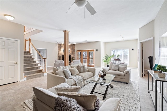 living room with decorative columns, baseboards, a ceiling fan, and stairs