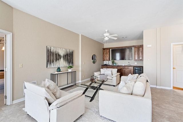 living area with wine cooler, baseboards, indoor wet bar, and ceiling fan