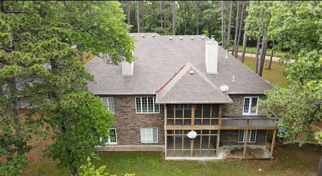 back of property featuring a patio area, a sunroom, and a chimney