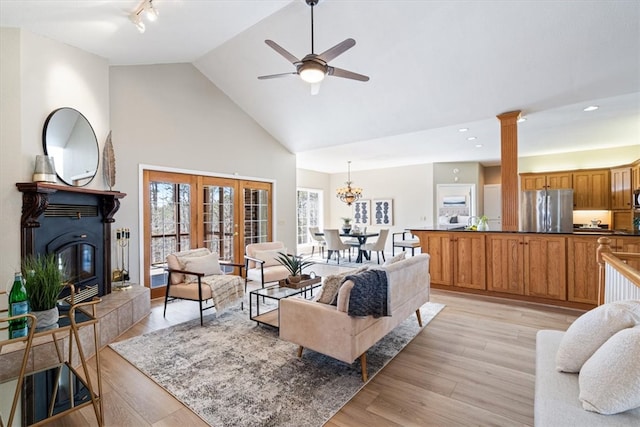 living room with track lighting, a tile fireplace, light wood-style floors, high vaulted ceiling, and a ceiling fan