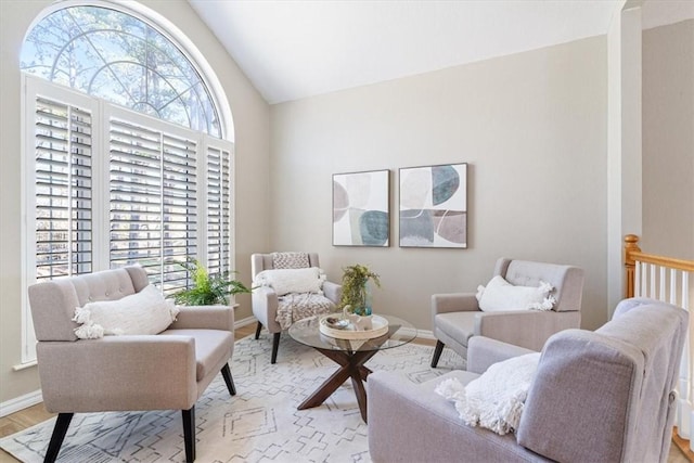 sitting room featuring light wood-type flooring, baseboards, and vaulted ceiling