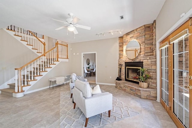 living room featuring a ceiling fan, visible vents, baseboards, a fireplace, and stairs