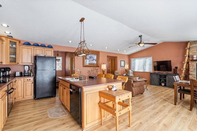 kitchen featuring light wood finished floors, a breakfast bar, lofted ceiling, black appliances, and a sink