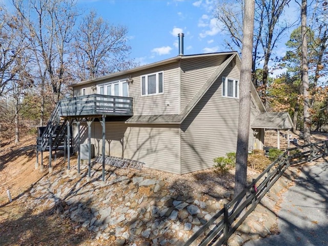 rear view of property with cooling unit, a wooden deck, and stairs