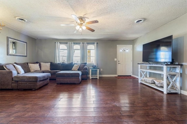 living room featuring visible vents, wood-type flooring, baseboards, and a ceiling fan