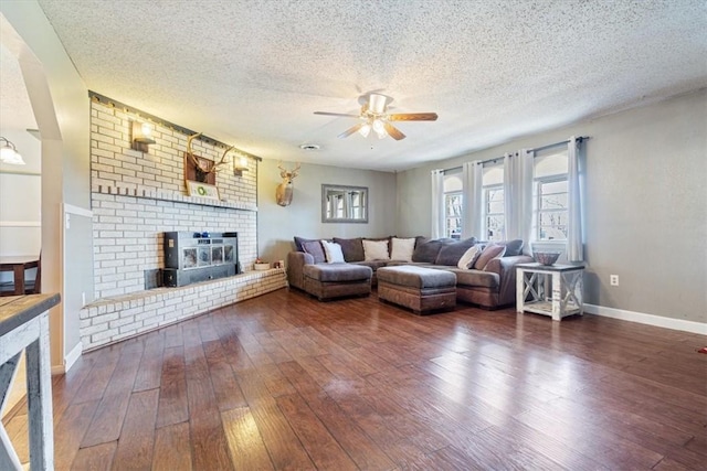 living room featuring baseboards, a fireplace, dark wood-style flooring, and a textured ceiling