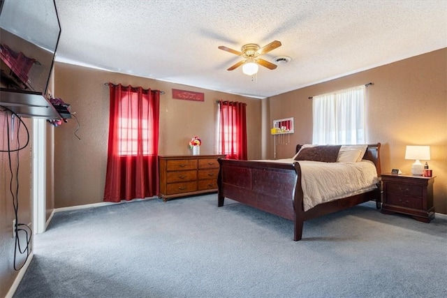 carpeted bedroom featuring ceiling fan and a textured ceiling