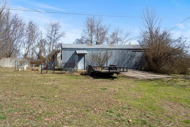 exterior space featuring an outbuilding, a lawn, metal roof, and an outdoor structure