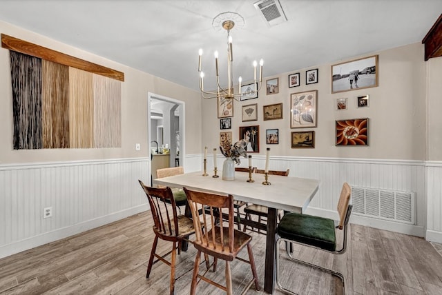 dining space featuring visible vents, a wainscoted wall, and light wood-style flooring