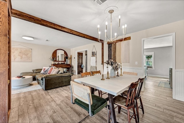 dining space with visible vents, a wainscoted wall, beam ceiling, light wood-style floors, and a notable chandelier