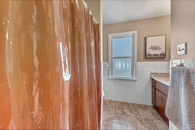 bathroom with tile walls, a wainscoted wall, toilet, and vanity