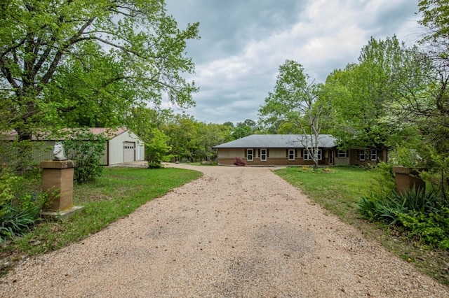 view of front of home with an outbuilding, a garage, a front lawn, and dirt driveway