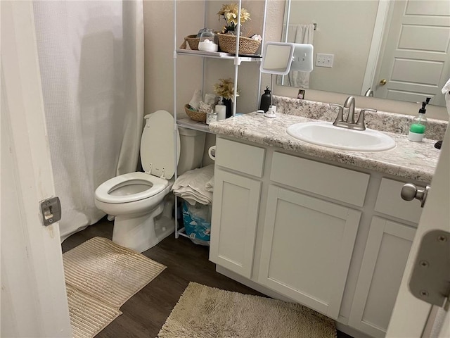 full bath with toilet, wood finished floors, and vanity