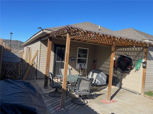 rear view of property with fence, roof with shingles, outdoor dining space, a pergola, and a patio