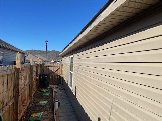 view of side of home with a mountain view and fence